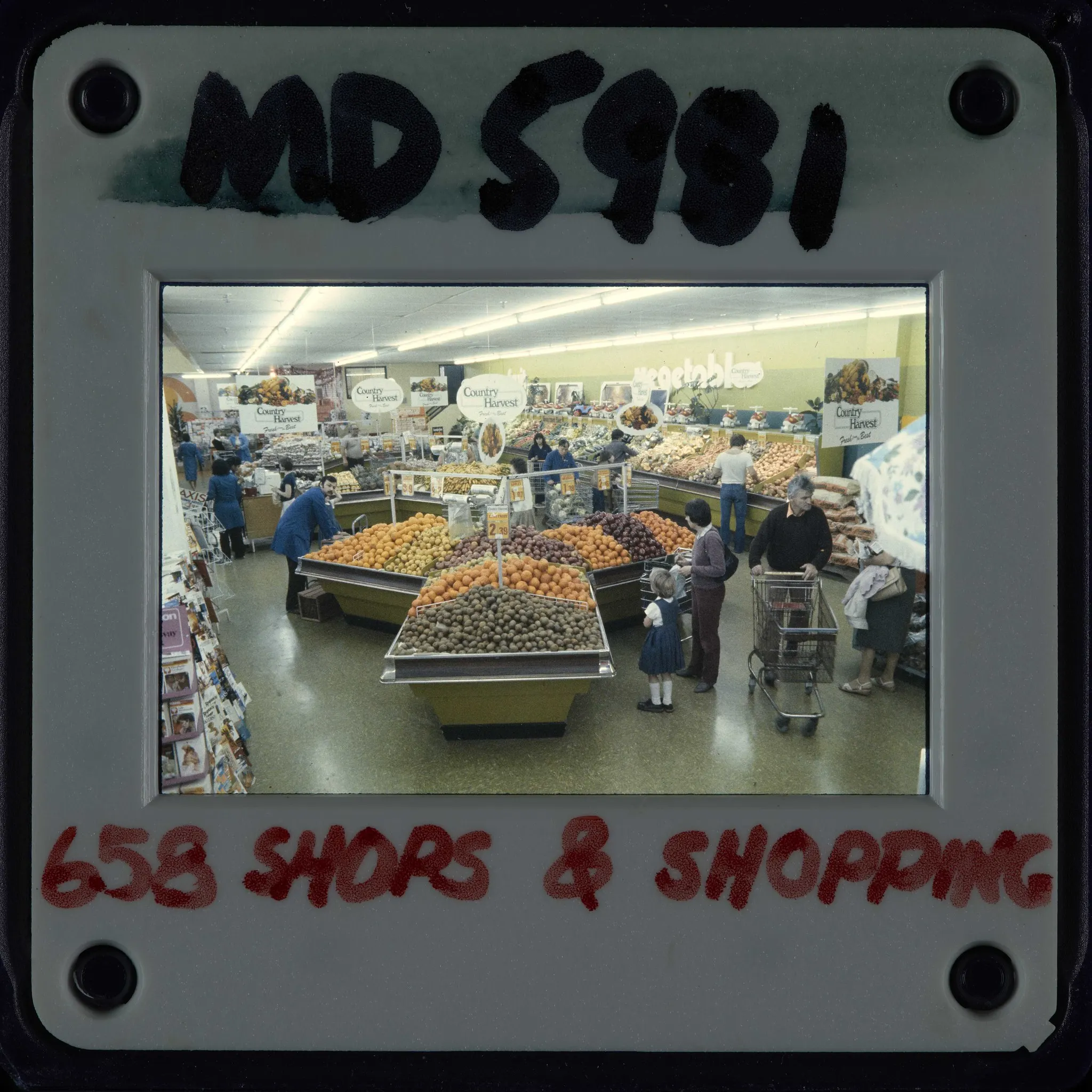 Shoppers with trolleys beside full fruit and vegetable displays in a Kilbirnie supermarket in 1983.