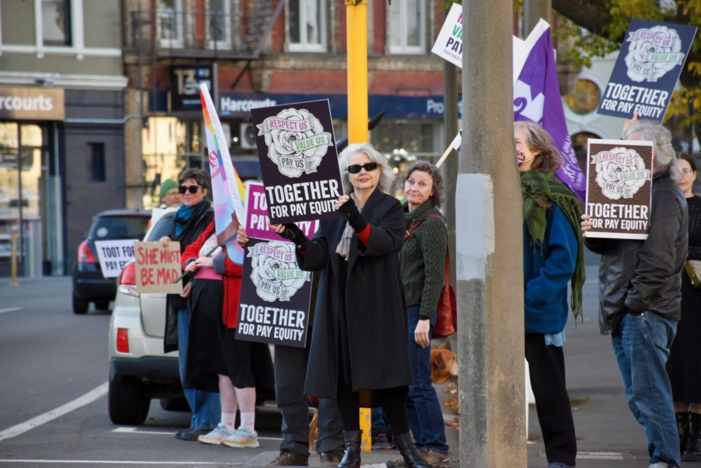 People holding Together for Pay Equity signs at a street demonstration.