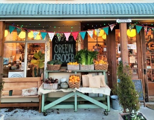 Fruit and vegetables displayed outside a greengrocer beneath colourful bunting.
