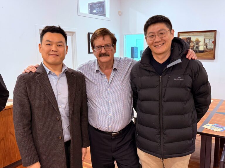 Three men posing together indoors.