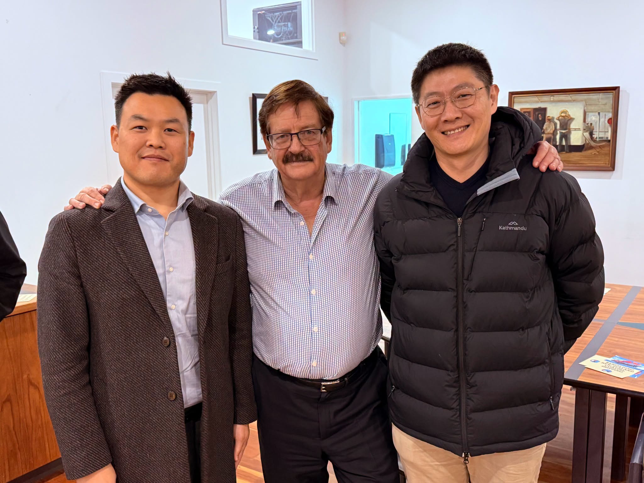 Three men posing together indoors.