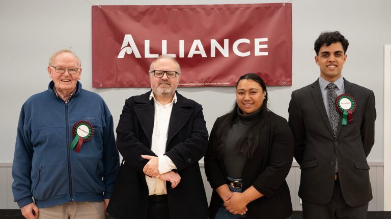 Four Alliance candidates standing together in front of an Alliance banner.